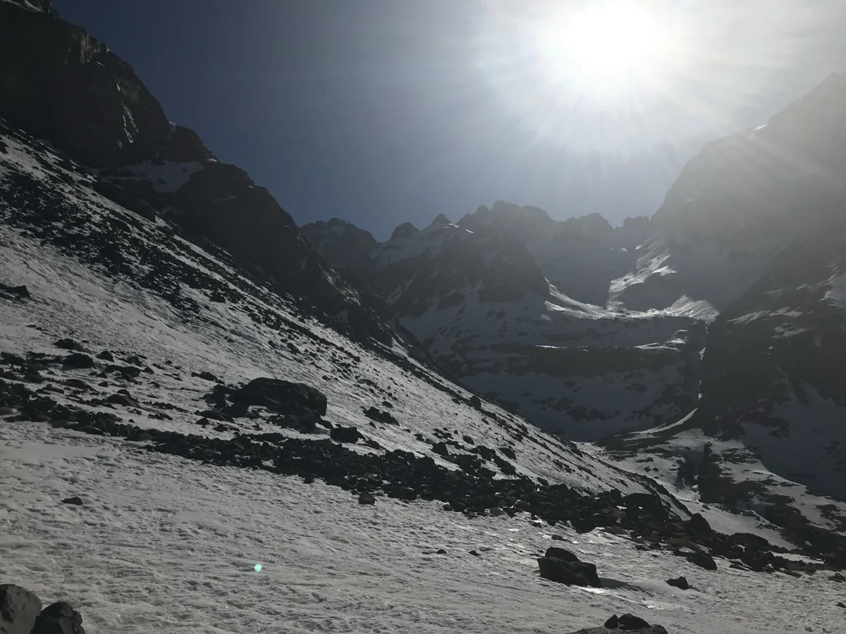 Sunlight over an icy trail between steep rocky slopes on Mount Toubkal