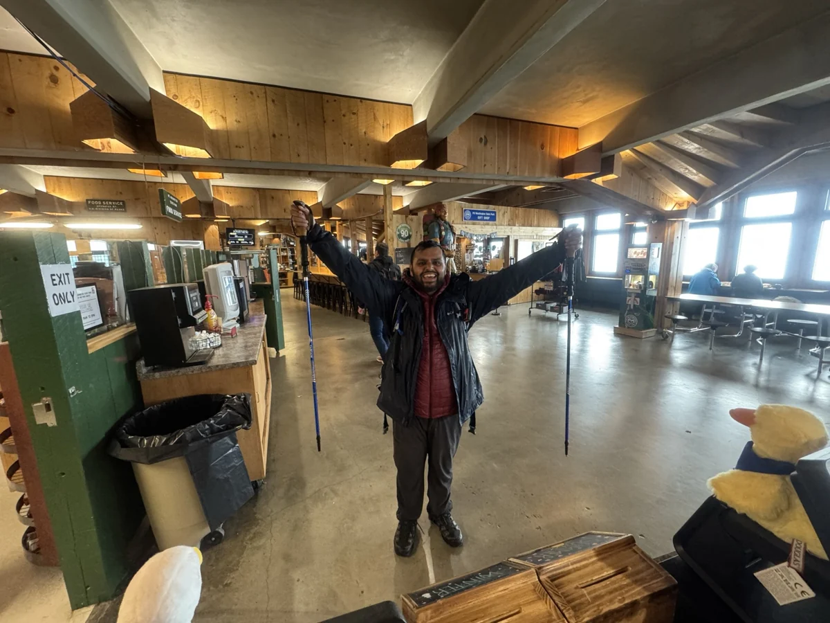 Hamdan standing with arms outstretched inside the Mount Washington summit cafeteria