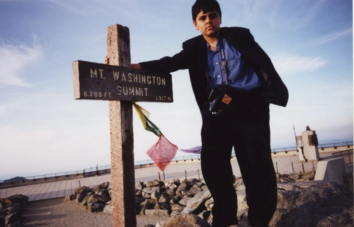 A young Hamdan standing beside the Mount Washington summit sign